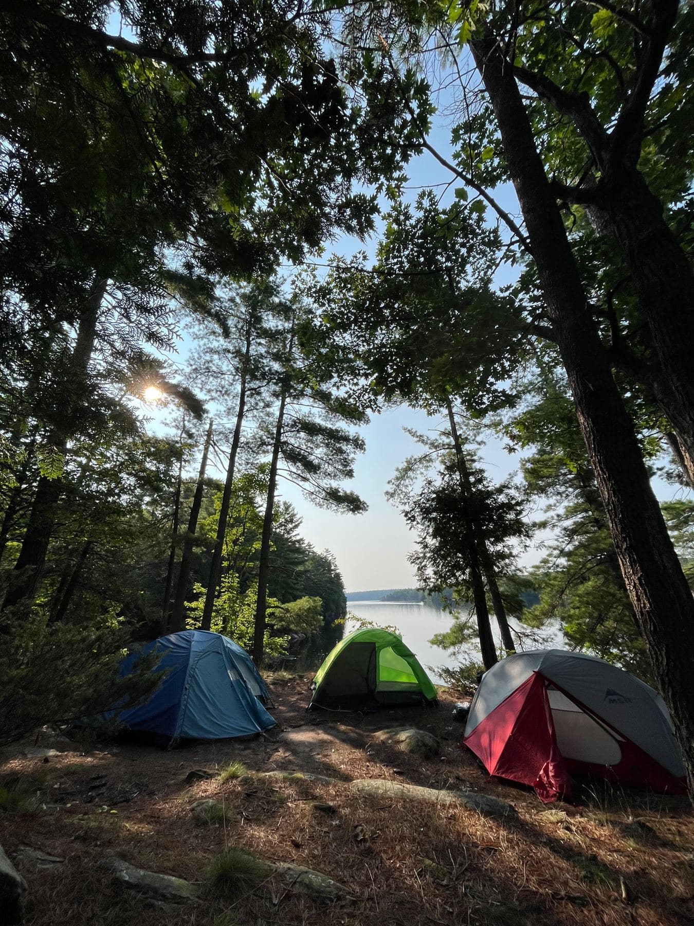 Three tents at a lakeside campsite